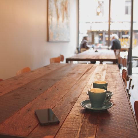 A coffee cup on a wooden café table by the window (mood photo)