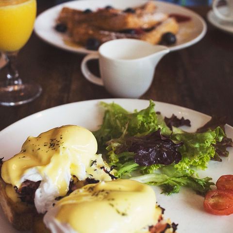 Eggs Benedict with salad and orange juice on a brunch table (mood photo)